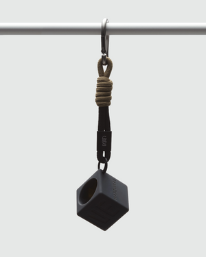GAMINE HARDWARE Noir — black cube parfum vessel hanging from knotted tan rope and black strap, suspended from a steel bar. Made for motion, engineered for utility